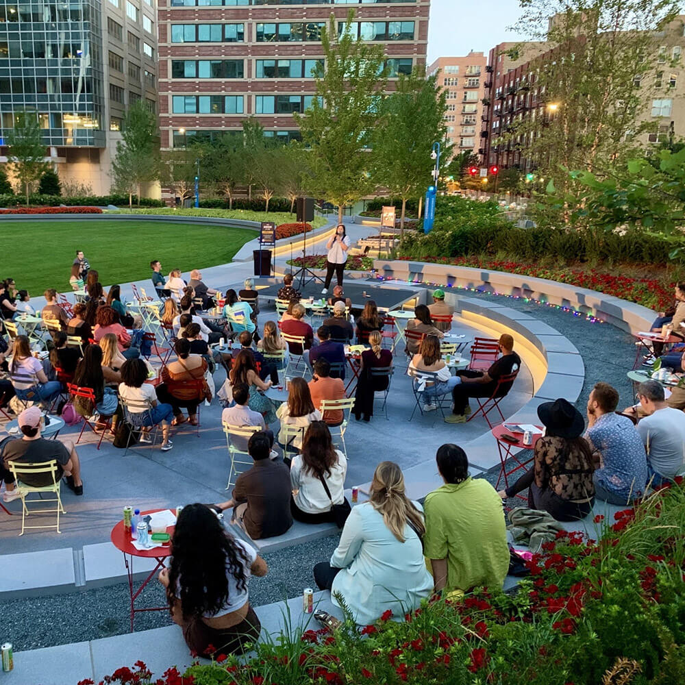 A person speaks to a small crowd seated at tables