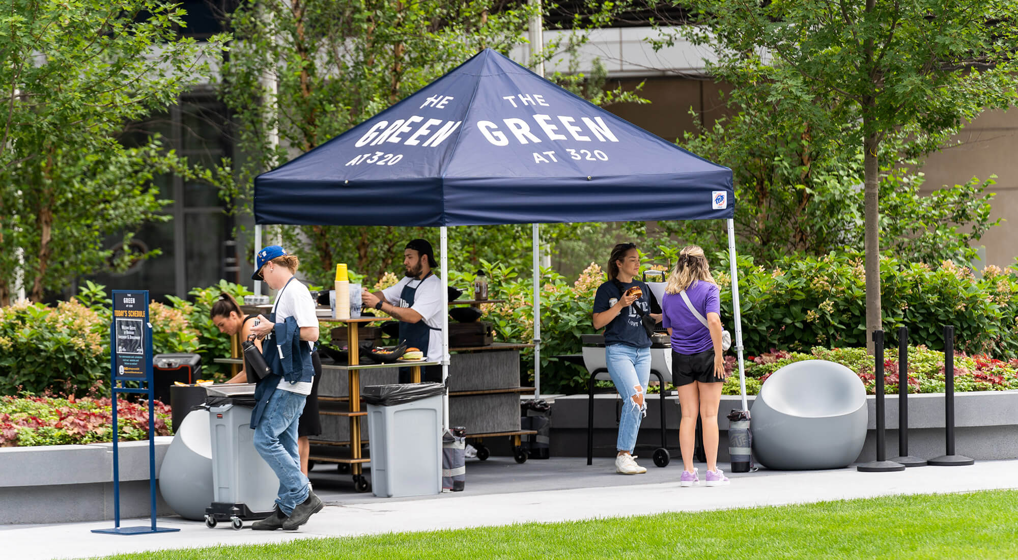 Food vendors work an event under a branded tent