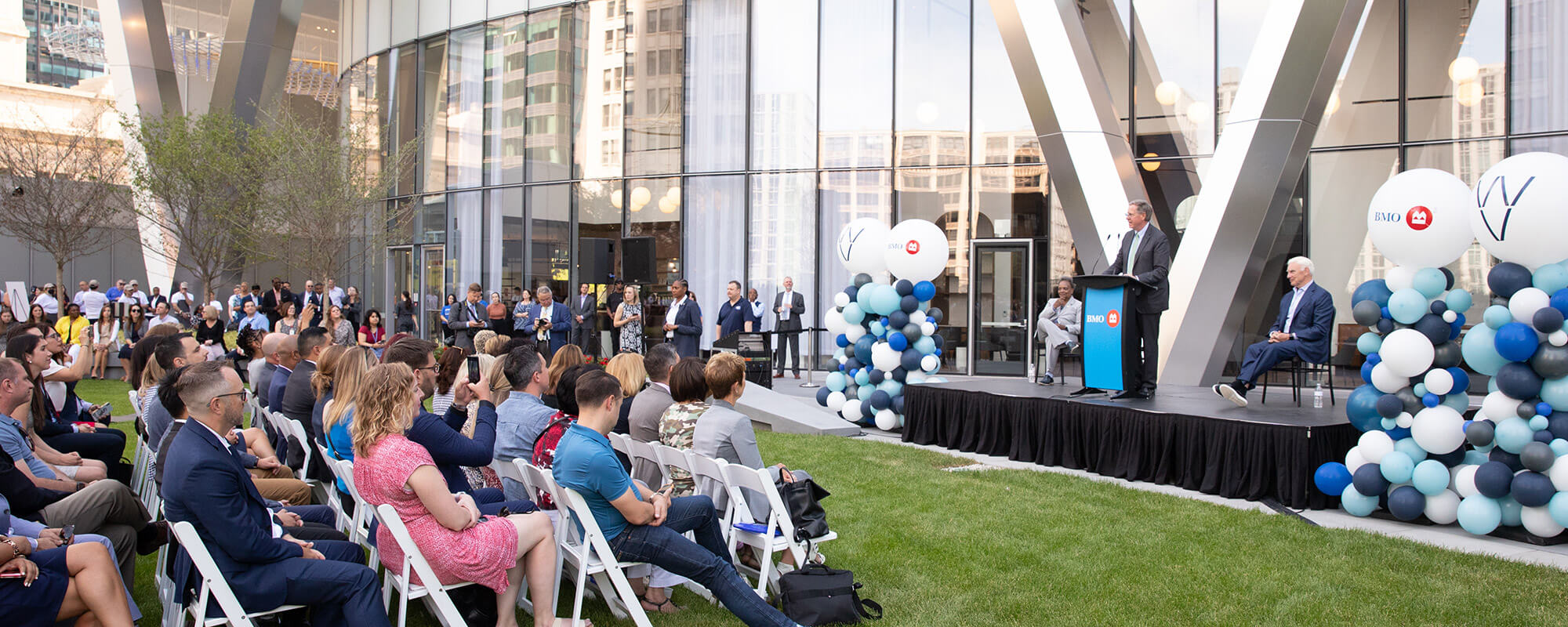 A man speaks at a decorated podium during a large event