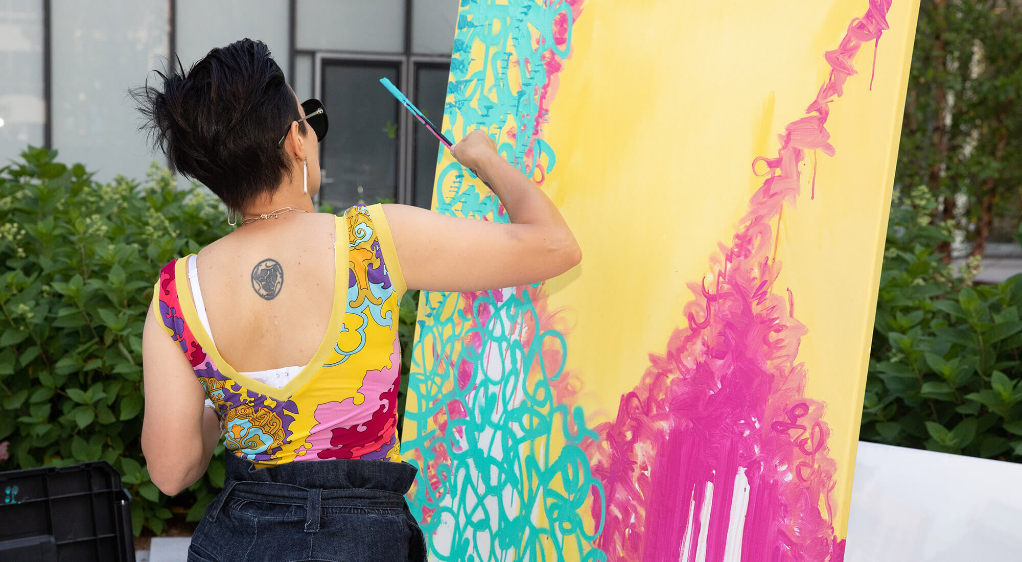 A woman paints a vibrant artpiece on a canvas